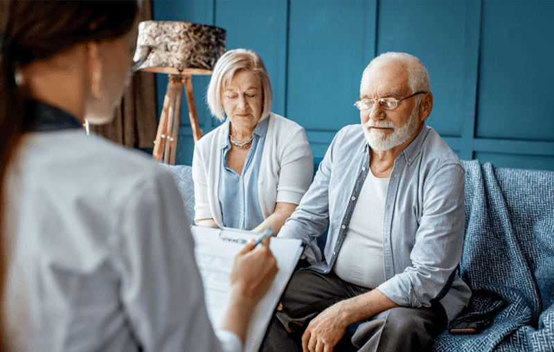 A man and woman sitting in front of another man.