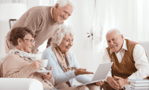 A group of people sitting around a laptop.