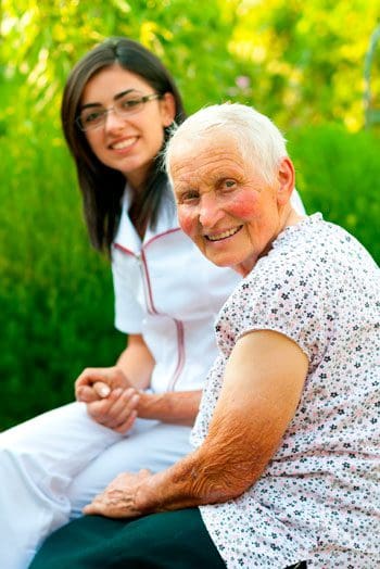 A woman and an older person sitting on grass.